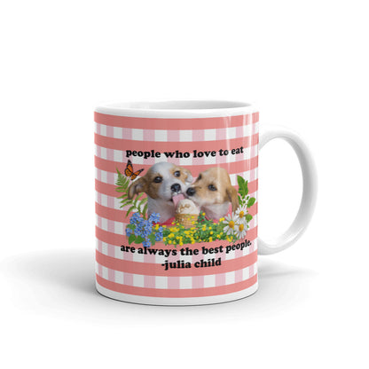 A mug with red plaid and a quote from Julia Child "people who love to eat are always the best people" with two doggies licking up an ice cream treat sourrounded by flowers, leaves, ferns, and an orange butterfly